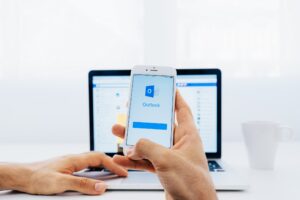 Mann prüft seine E-Mails auf seinem Handy und seinem Laptop